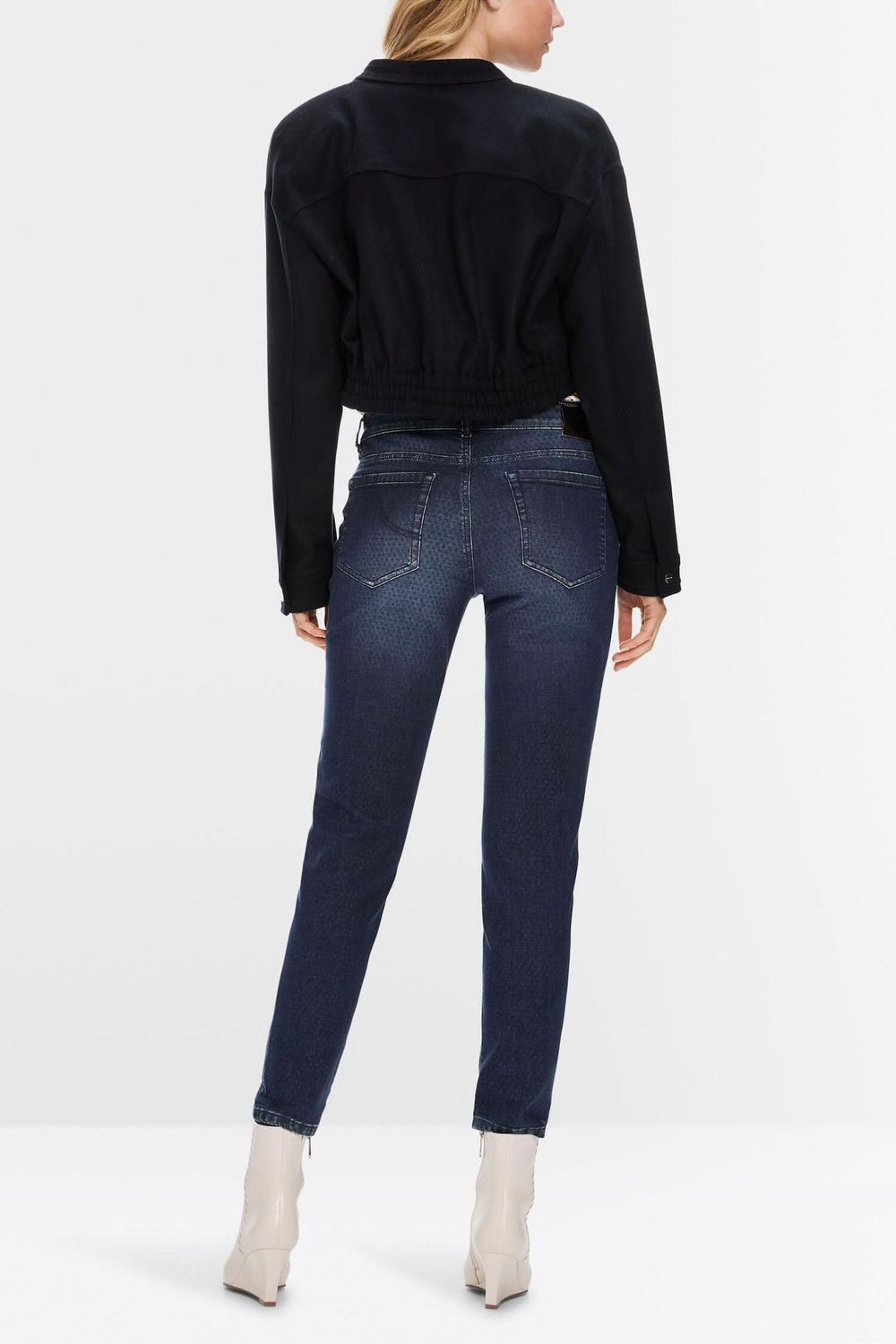 Femme de dos portant un jean slim fit Silvi avec un haut noir, vu dans un décor minimaliste.