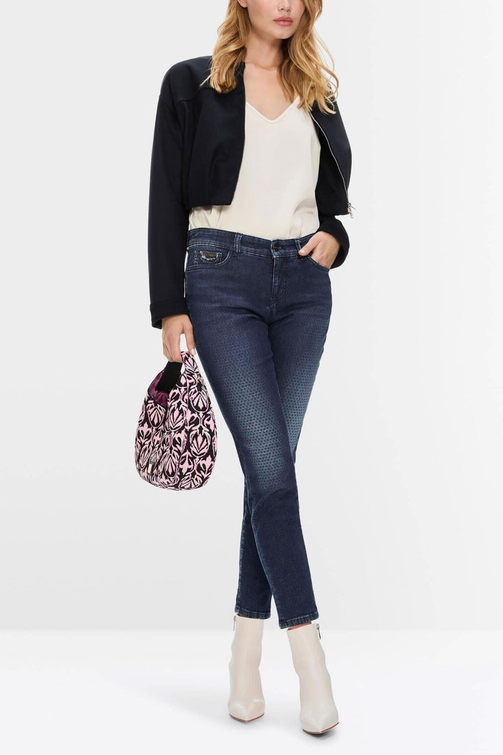 Femme portant des jeans slim foncés avec une veste courte et un sac à main élégant.