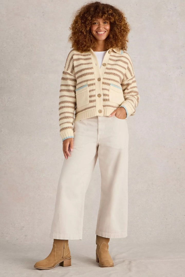 Jean Tia court à jambes larges porté avec un cardigan rayé et des bottes, affichant une silhouette confortable et structurée.