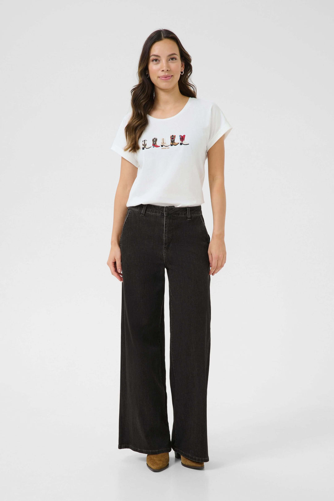 Femme portant un jean à jambe large noir avec un t-shirt tendance, favorisant un look décontracté et élégant.