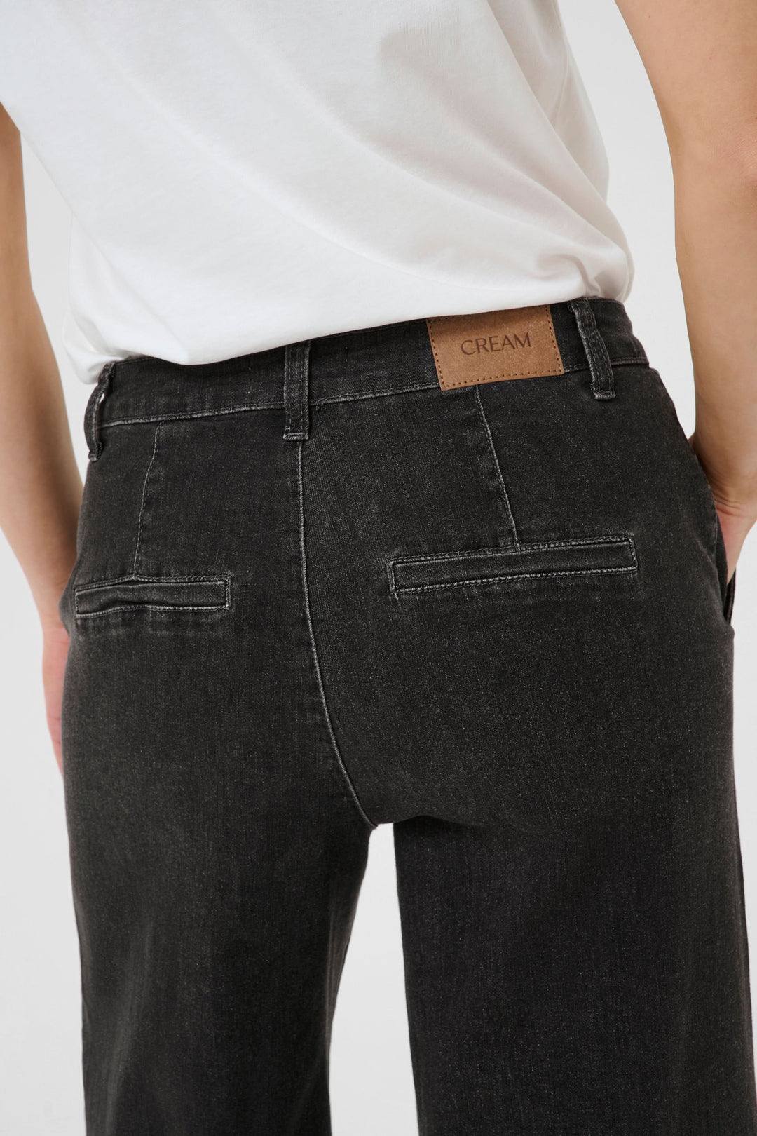Jean à jambe large noir avec étiquette CREAM, taille mi-haute et poches arrière.