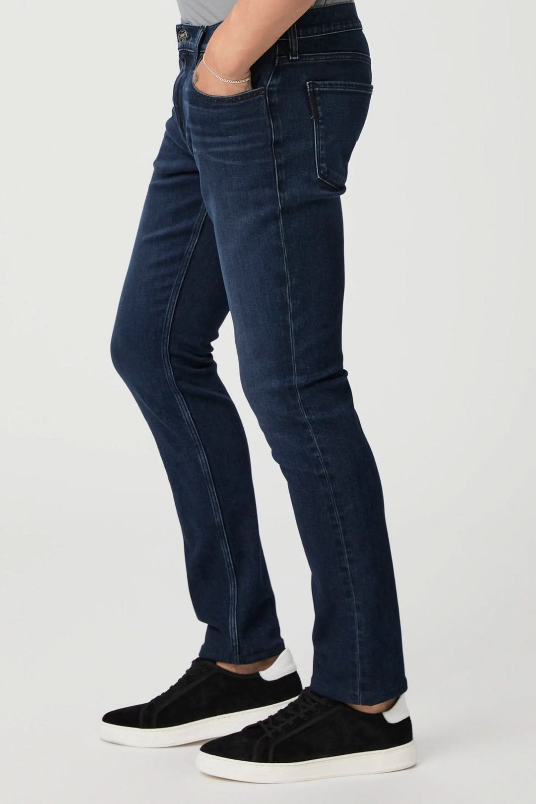 Jean ajusté vintage en denim foncé, coupe classique, porté avec des baskets noires, style décontracté chic.