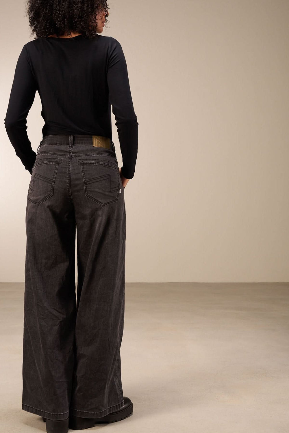 Vue arrière d'un jean coupe large avec taille mi-haute et jambes amples, porté par une femme. Idéal pour un look décontracté.