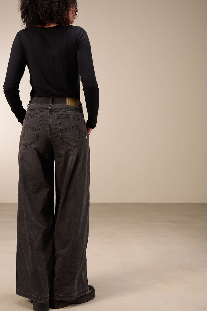 Vue arrière d'un jean coupe large avec taille mi-haute et jambes amples, porté par une femme. Idéal pour un look décontracté.