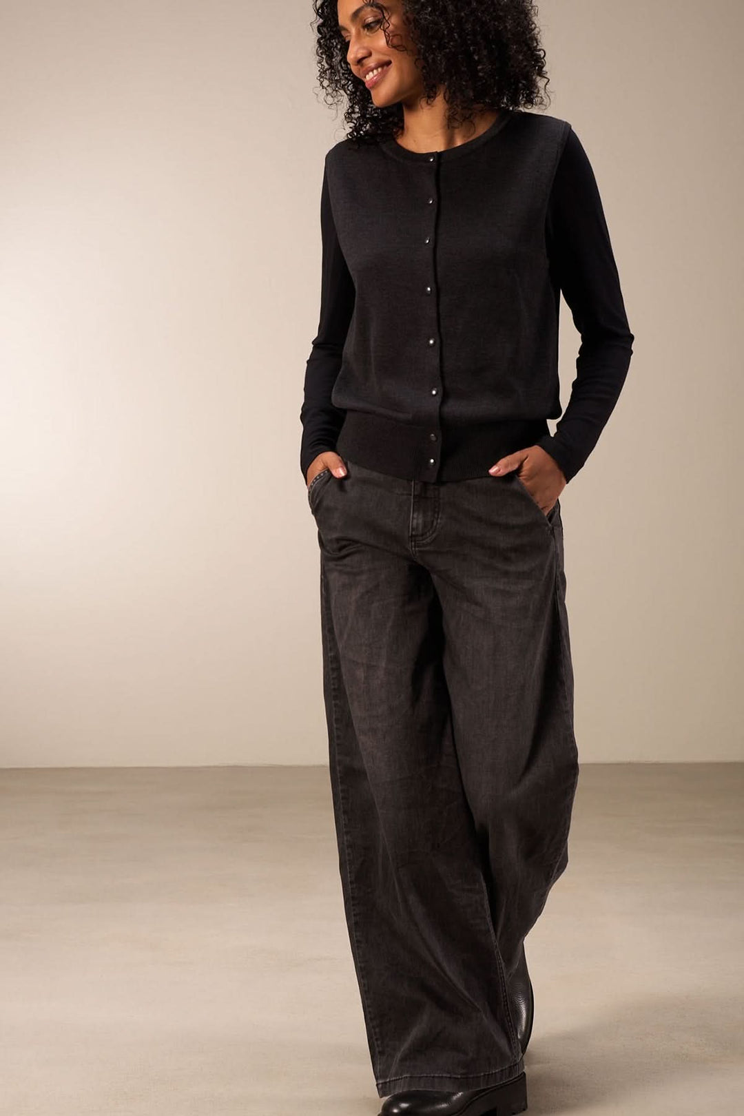 Jean coupe large, taille mi-haute avec jambes amples, porté avec un haut noir pour un style confortable et élégant.