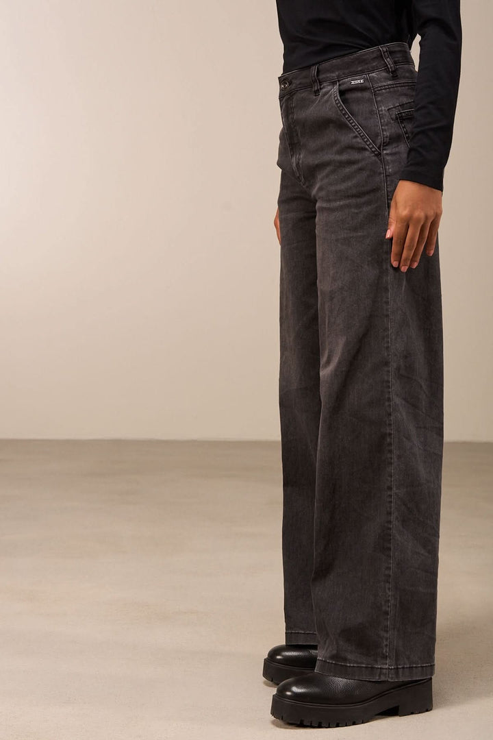 Vue latérale d'un jean coupe large gris foncé avec taille mi-haute et jambes amples, idéal pour un look décontracté ou habillé.