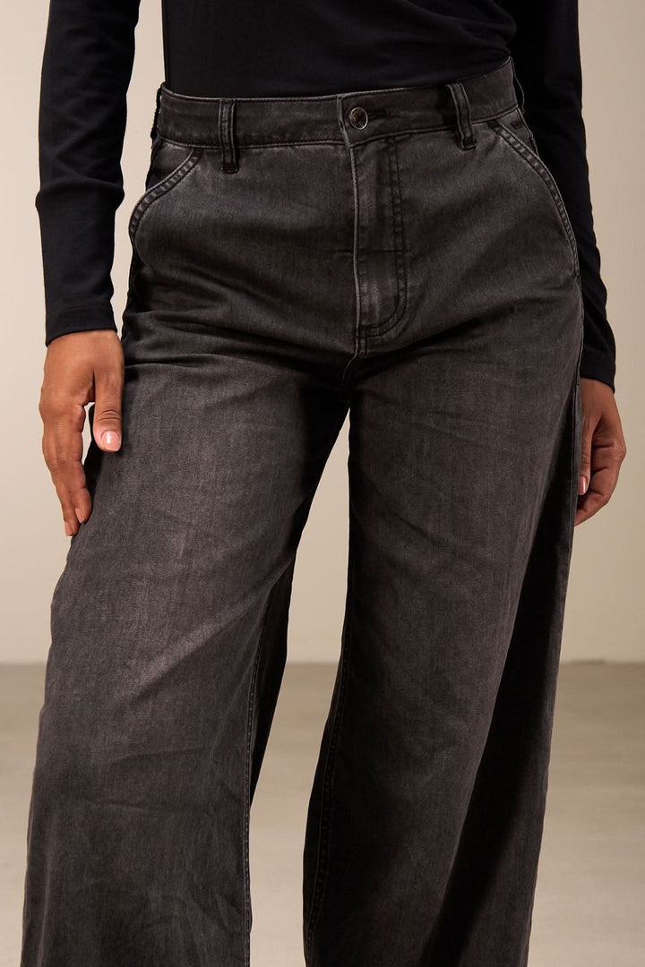 Jean coupe large noir avec taille mi-haute et jambes amples portées par un modèle sur fond neutre.