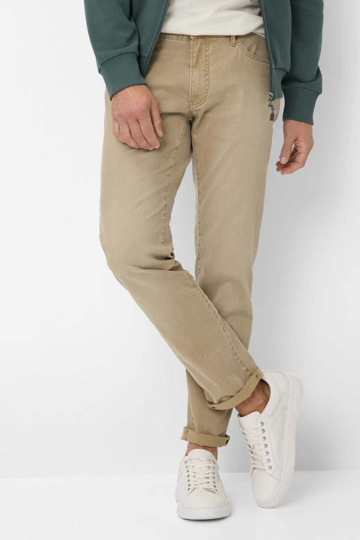 Jean moderne beige à cinq poches porté avec un chandail et des chaussures blanches, look décontracté et soigné.