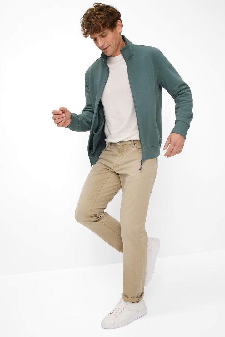 Homme en tenue décontractée avec veste verte et pantalon beige, stylé et confortable.