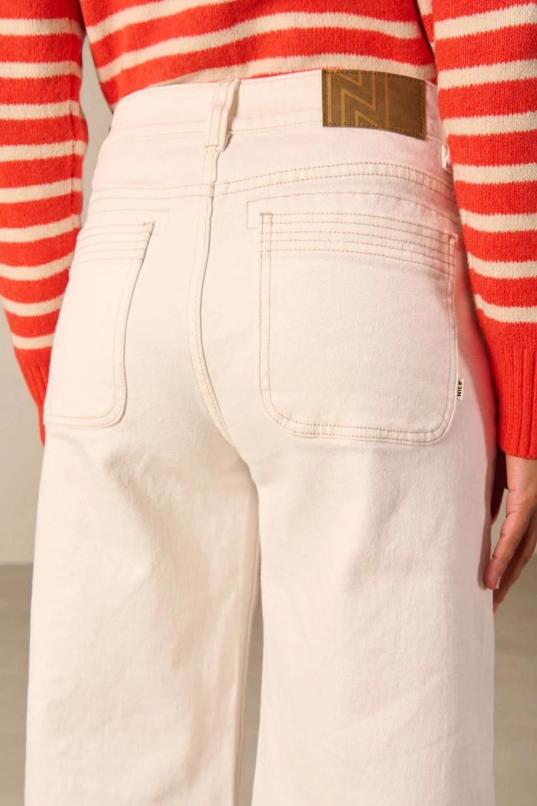 Jean jambe large taille haute en denim blanc avec poches à l'avant, idéal pour un style rétro et moderne, porté avec un pull rayé rouge et blanc.