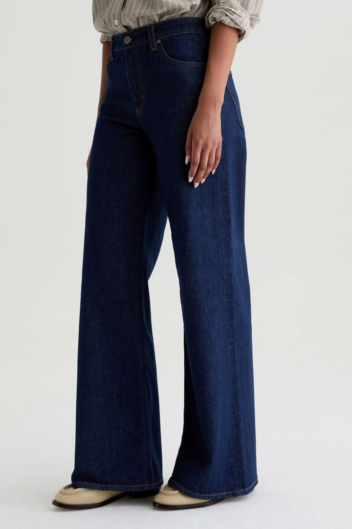 Jean à jambe large en denim bleu avec coupe taille haute et cinq poches, idéal pour un style élégant et moderne.