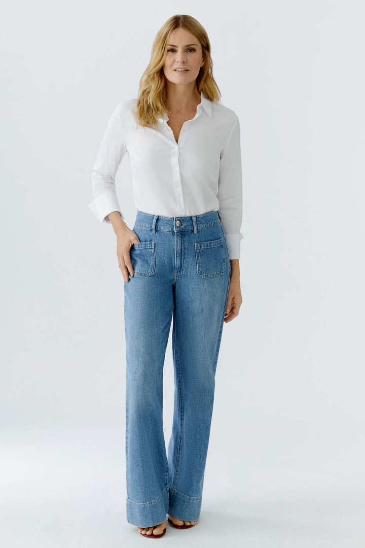 Jean large à taille haute porté avec blouse blanche pour un look moderne et élégant