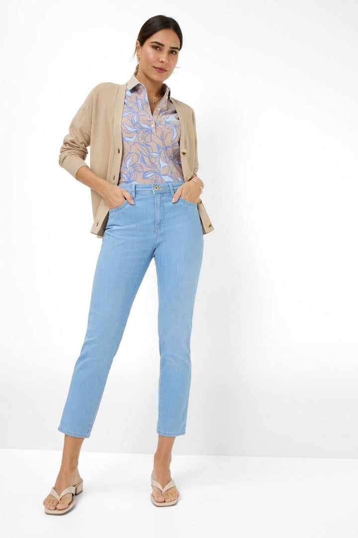 Femme portant le jean MARY S bleu clair, associé à un chemisier et cardigan, affichant un style décontracté et élégant.