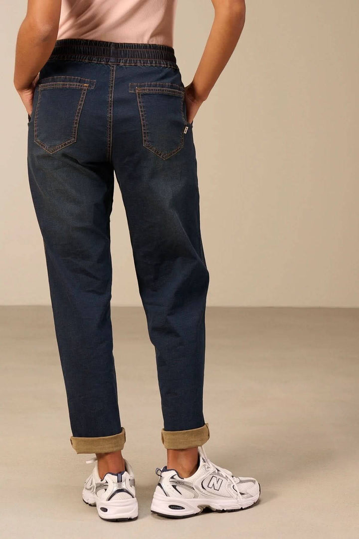 Vue arrière d'un jeanjogging à taille élastique avec coupe fuselée, soulignant un look casual chic avec des baskets blanches.