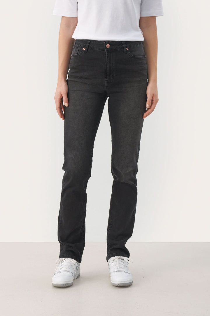 Jeans Ranas ajustés noir avec modèle classique à 5 poches, portés avec un t-shirt blanc et des baskets blanches.