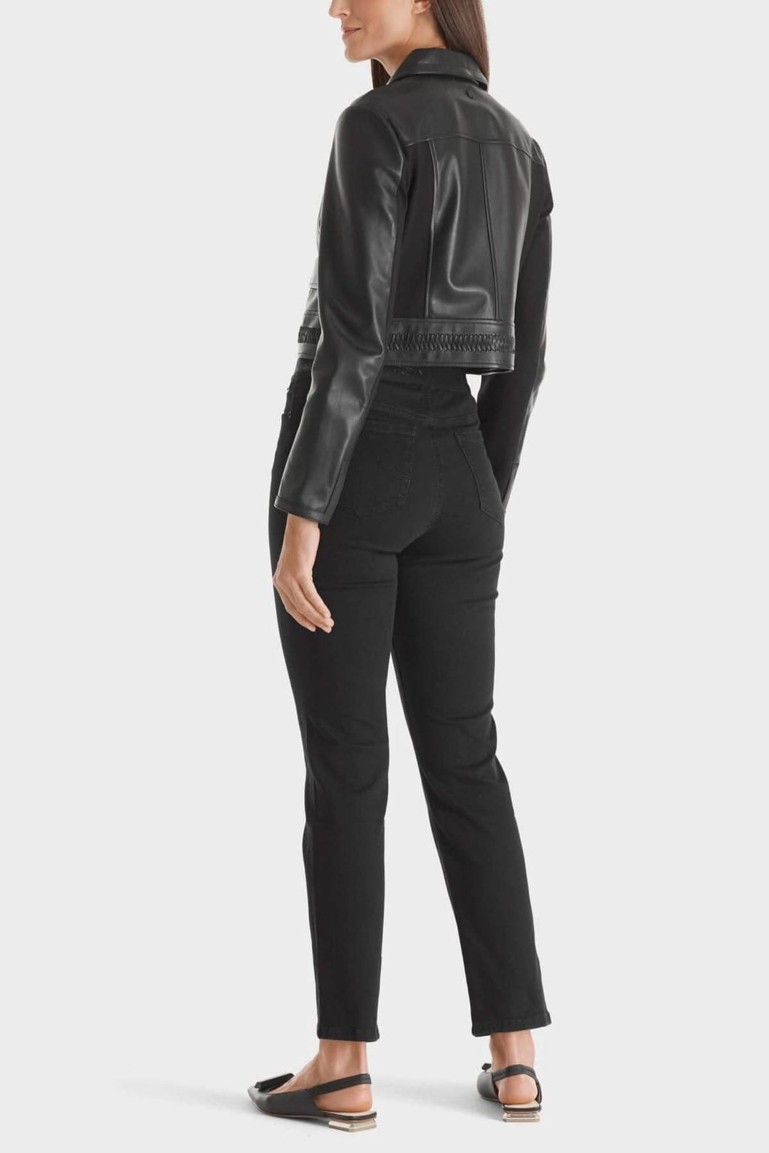 Femme portant une veste en cuir noire avec un jean noir, vue de dos, style moderne et décontracté.