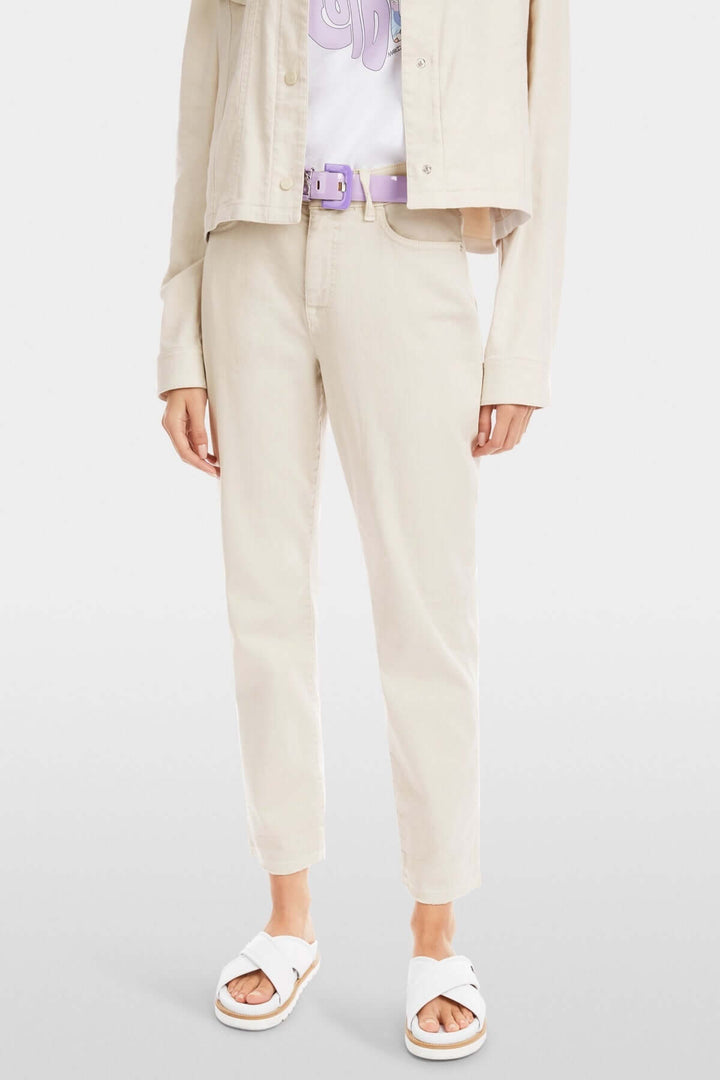 Jean Silea beige avec coupe fuselée, taille mi-haute et look casual-chic, porté avec un t-shirt et des sandales blanches.