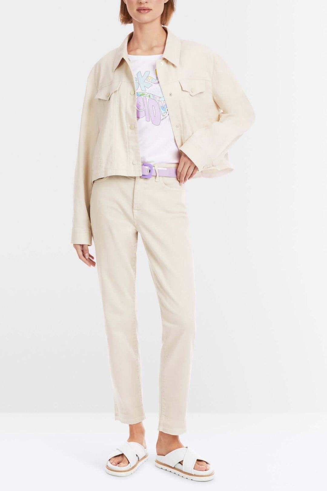 Femme portant un ensemble casual-chic avec une veste beige et un t-shirt coloré, complété par un jean fuselé.