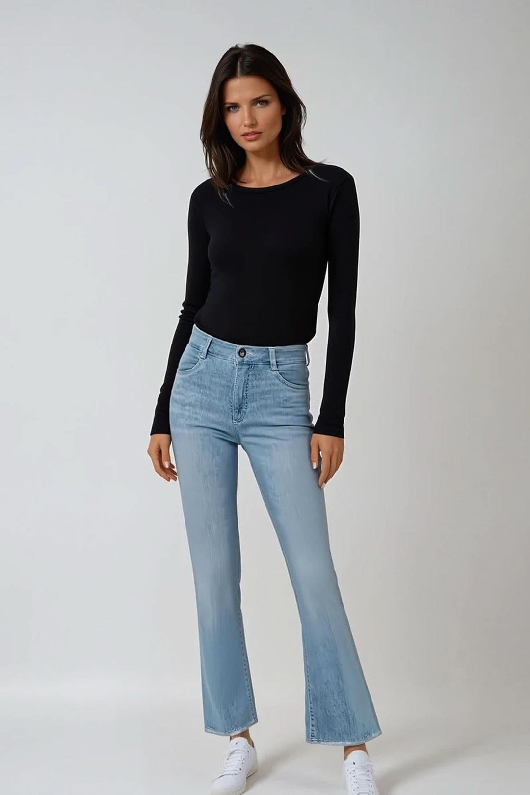 Model wearing SHAKIRA S bootcut jeans with a black top and white sneakers against a neutral background.