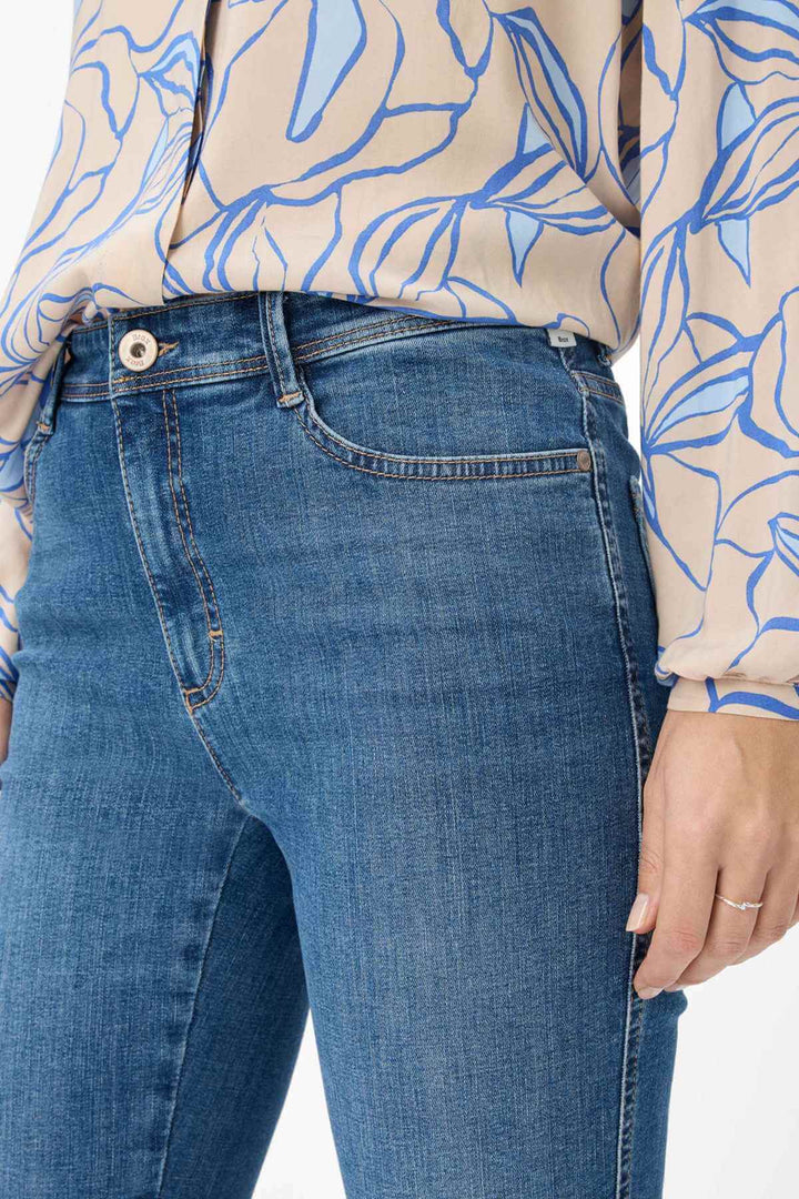 Détail du jeans classique MARY, cinq poches, coupe bootcut, tissu Vintage Stretch, porté avec un haut à motifs.