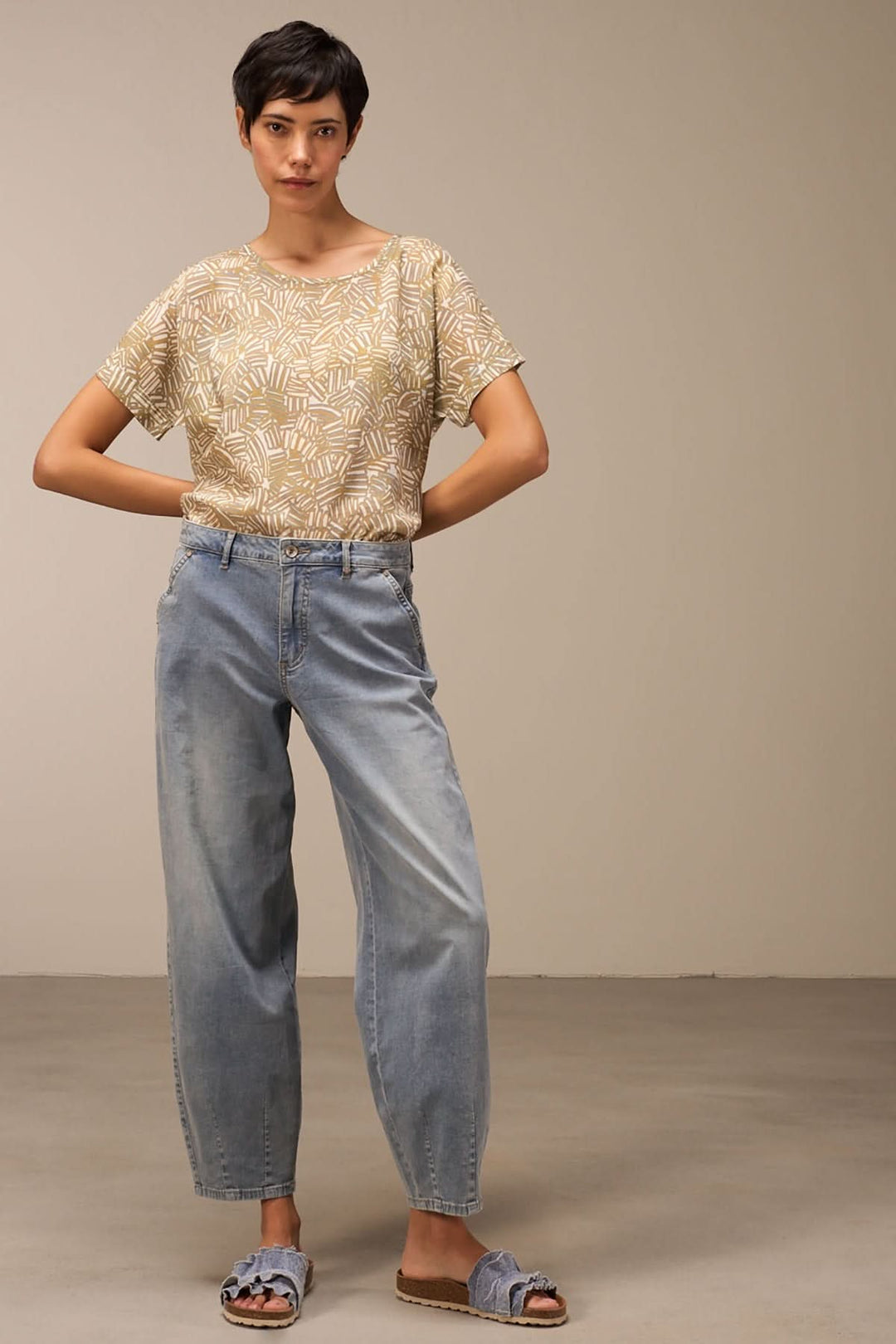 Femme portant un jean ample délavé et un t-shirt à motifs, style décontracté et vintage.