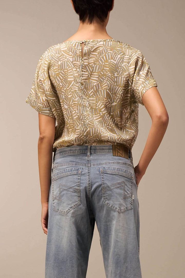 Femme dos portant un top à motif géométrique et un jean coupe ample délavé.