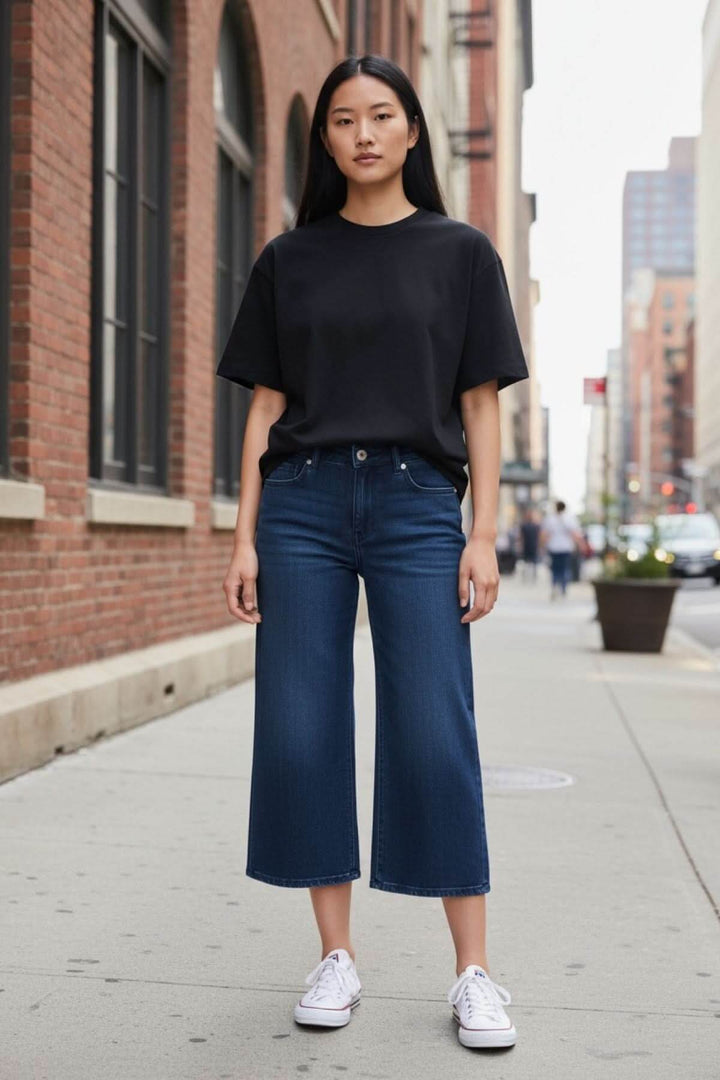 Femme portant un Jeans jambe évasée avec t-shirt noir, style décontracté et moderne, dans une rue urbaine.