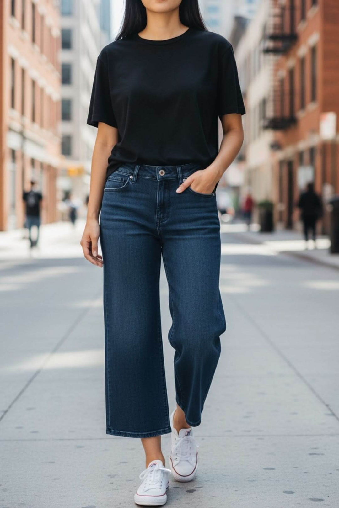 Femme portant un jeans jambe évasée avec t-shirt noir en ville, montrant une silhouette moderne et décontractée.