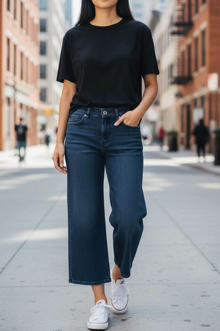 Femme portant un jeans jambe évasée avec t-shirt noir en ville, montrant une silhouette moderne et décontractée.