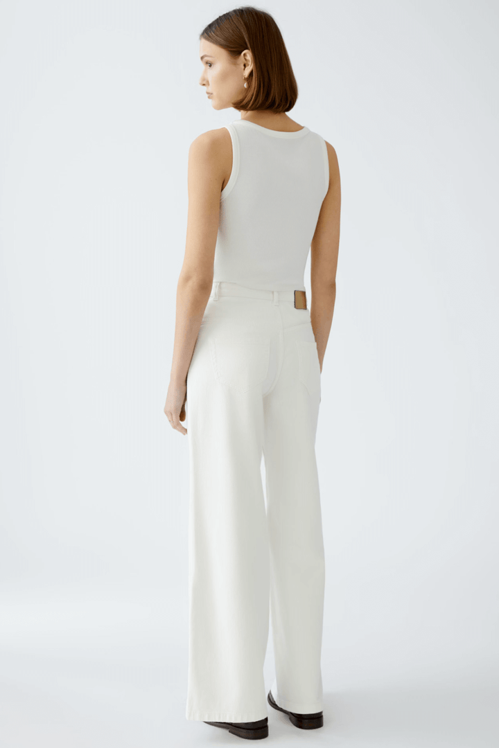 Femme vue de dos portant un jean blanc taille haute et un débardeur, affichant un look moderne et décontracté.