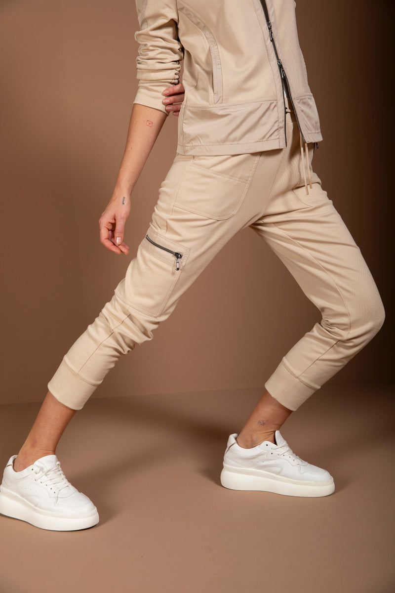 Jogging ajusté beige avec coupe moderne et détails fonctionnels, porté avec des sneakers blancs pour un look chic et confortable.
