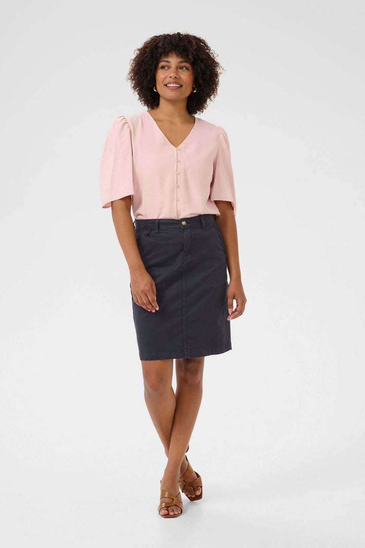 Jupe Berte droite courte portée avec un chemisier rose, coupe structurée et look moderne, idéale pour un style décontracté ou habillé.