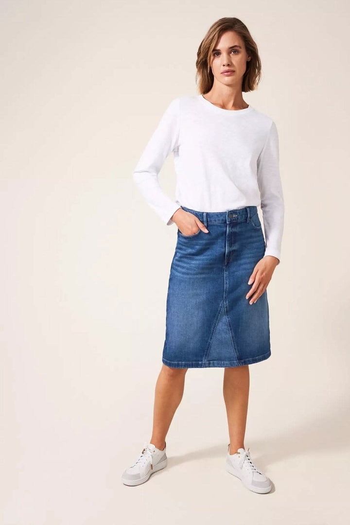 Jupe midi en jean pour femme, portée avec un t-shirt blanc et des baskets, style décontracté.