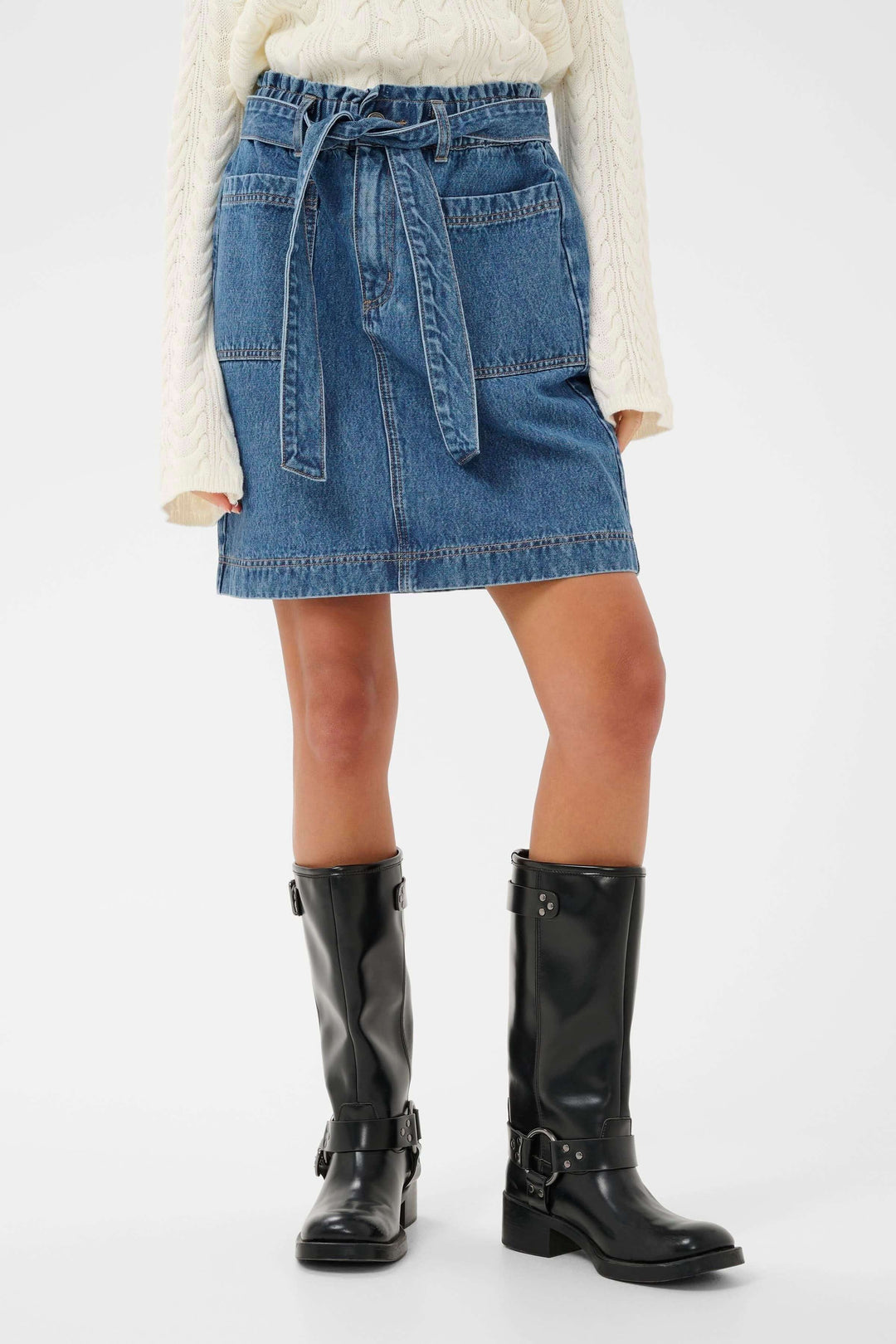 Jupe Klara en denim, coupe droite avec ceinture intégrée, silhouette structurée et féminine, portée avec des bottes noires.