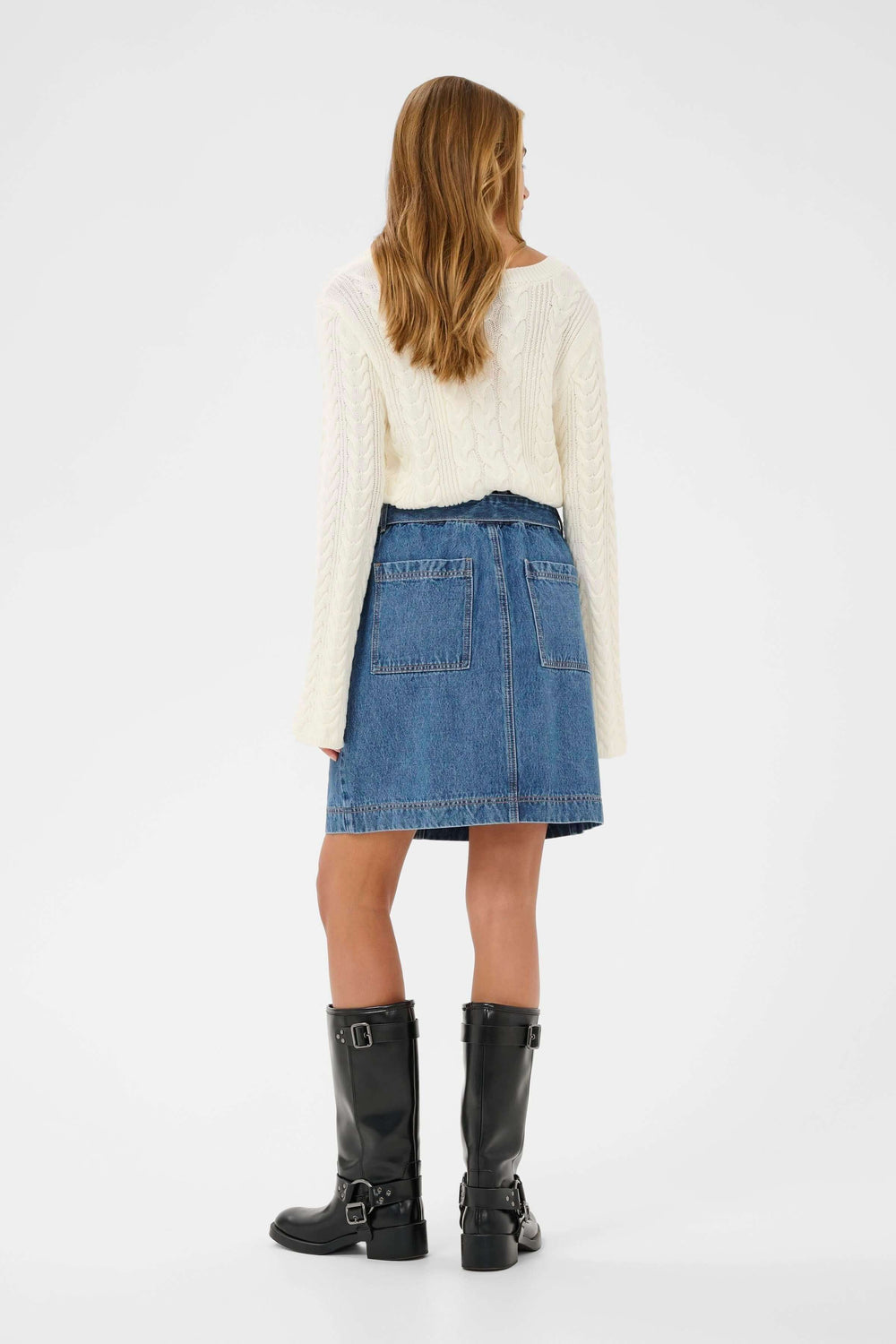 Vue arrière de la Jupe Klara en denim avec ceinture intégrée, portée avec un pull crème et des bottes noires.