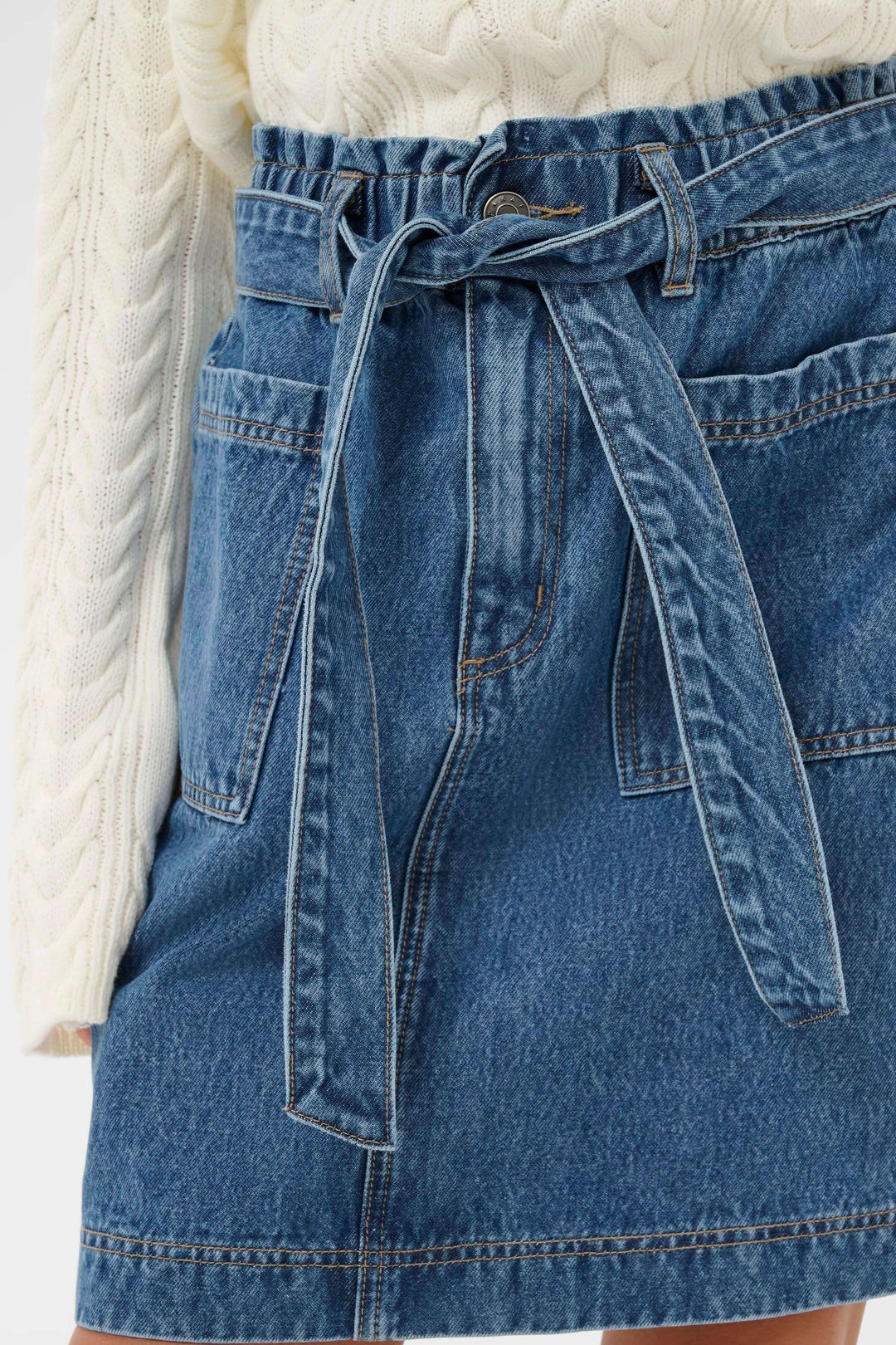 Jupe Klara en denim avec ceinture intégrée, silhouette moderne et féminine, coupe droite, taille haute, longueur au-dessus du genou.