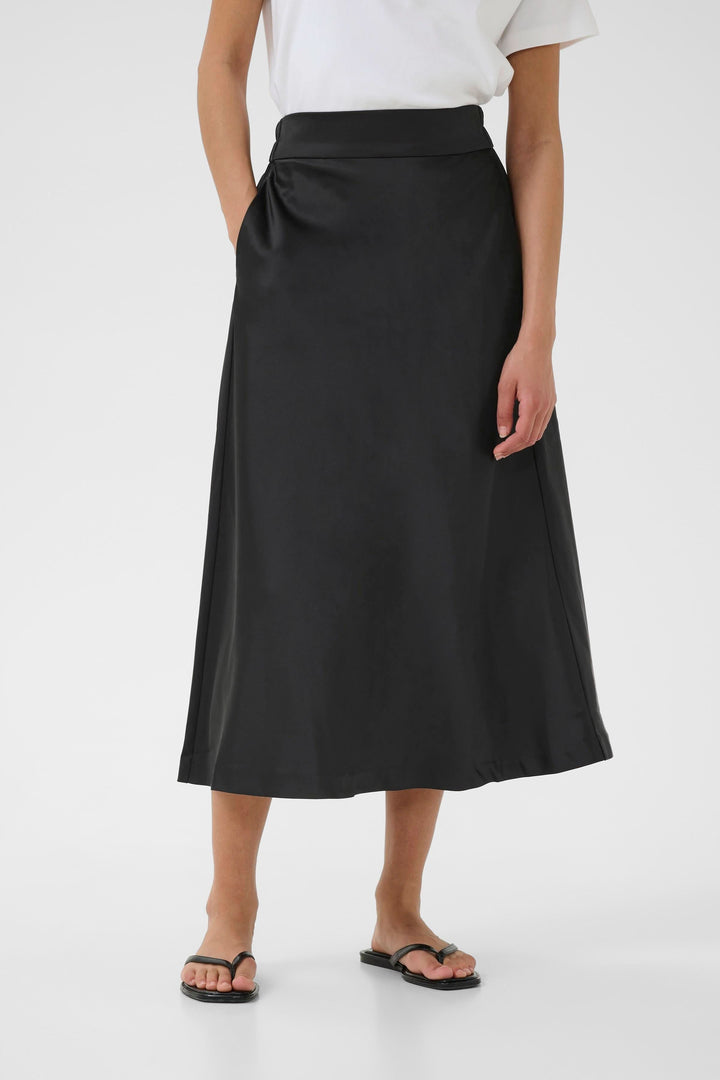 Jupe Zilky midi en noir, fluide et élégante, associée à un t-shirt basique pour un look minimaliste.