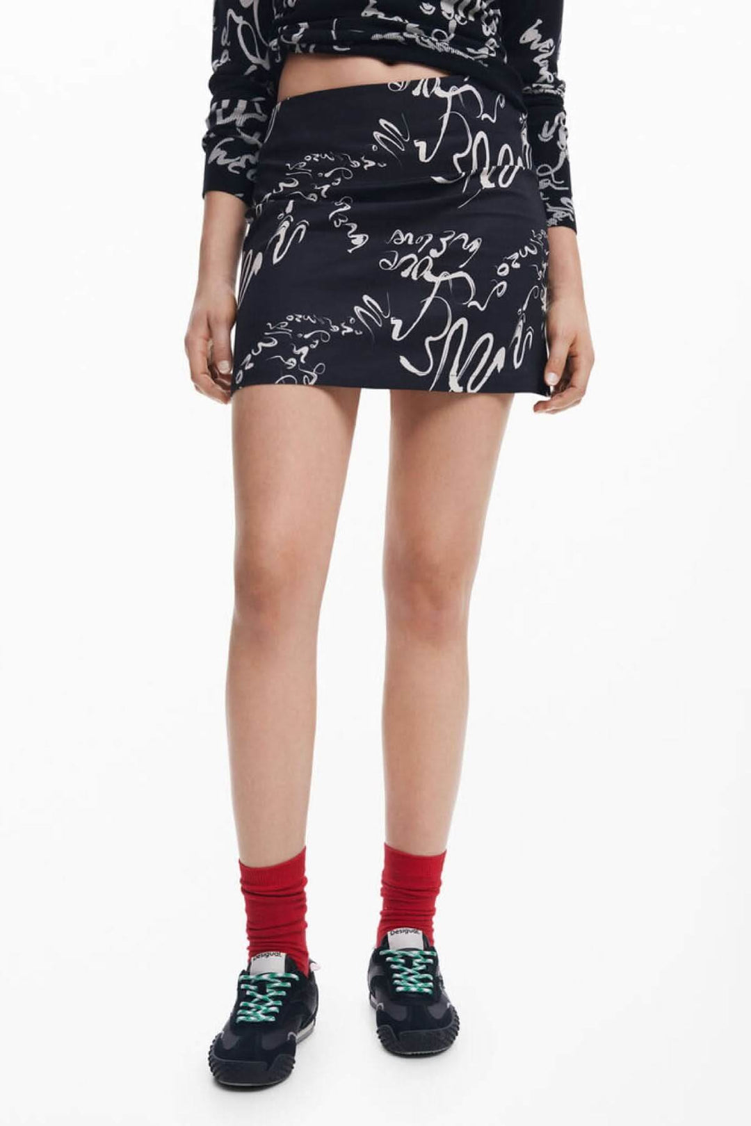 Jupe noire courte avec imprimé calligraphique blanc, style moderne, chic et tendance.