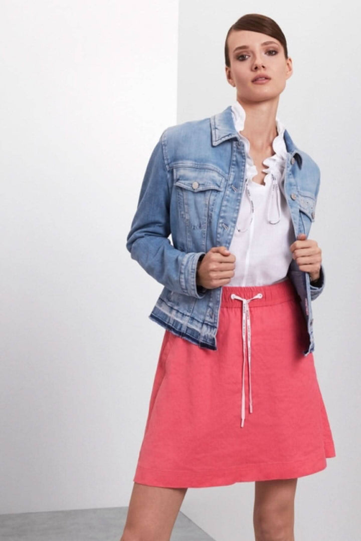 Femme portant une jupe courte rose et une veste en jean, style décontracté parfait pour l&