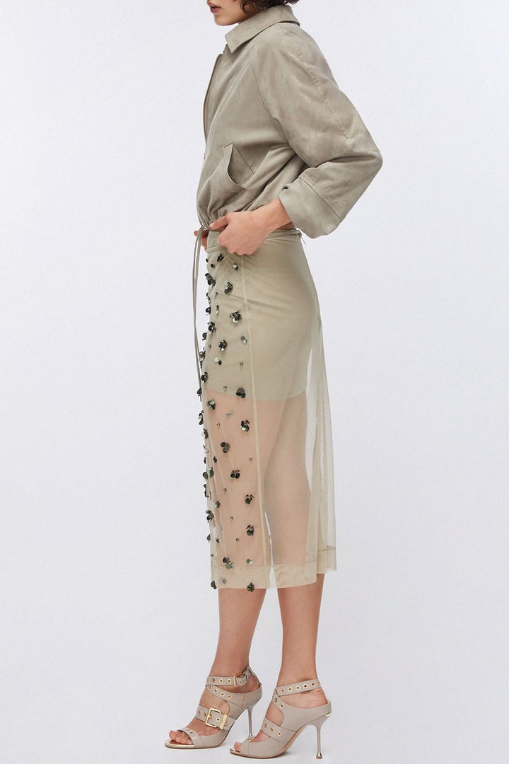 Jupe en maille transparente ornée avec applications décoratives, créant un effet texturé et une transparence moderne.