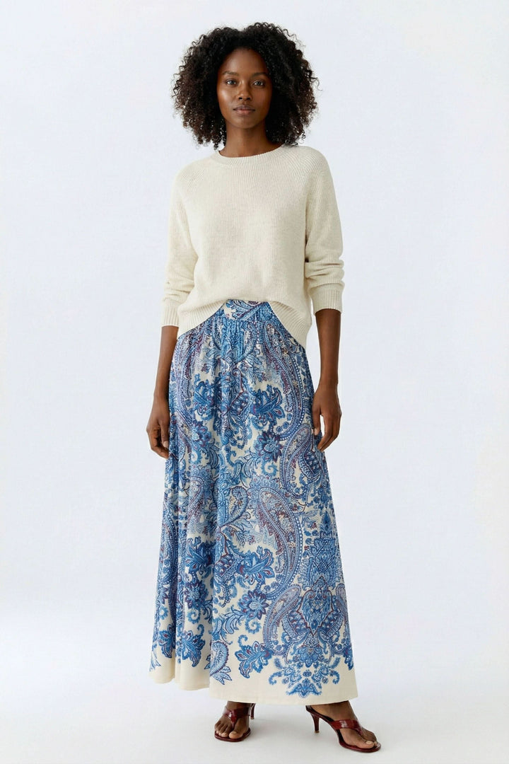 Femme portant une jupe longue imprimée à taille élastique au motif cachemire bleu, style bohème et élégant.