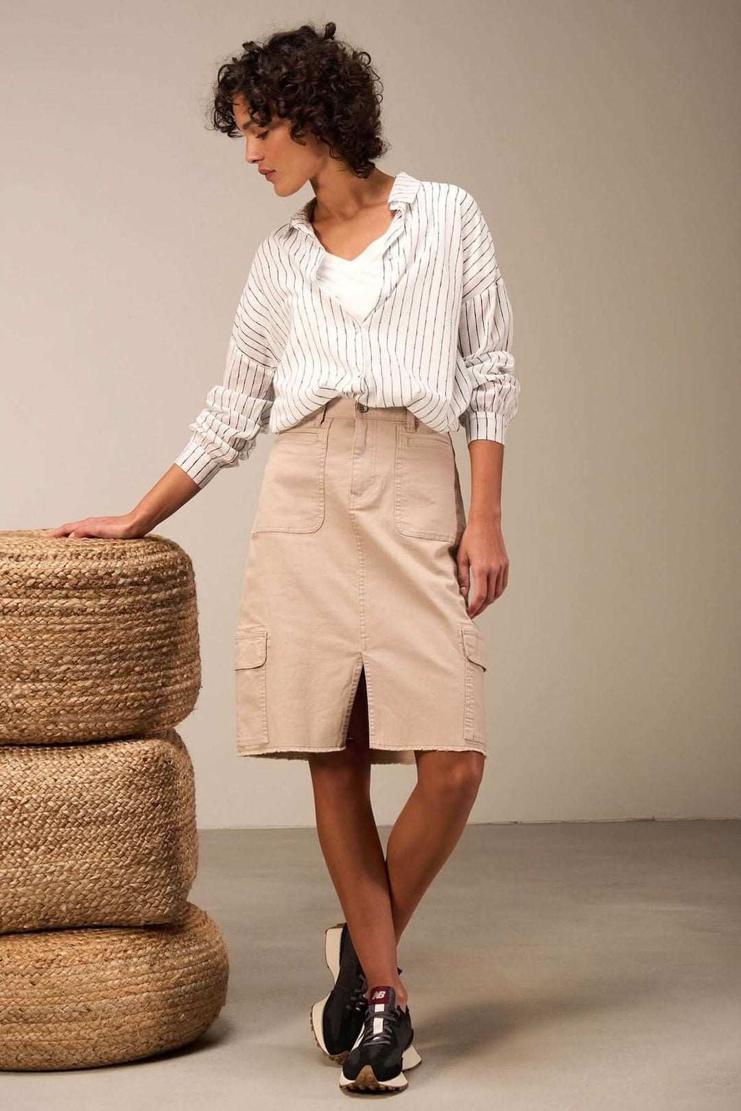 Jupe midi ajustée avec poches plaquées, portée avec une chemise rayée pour un style urbain tendance.