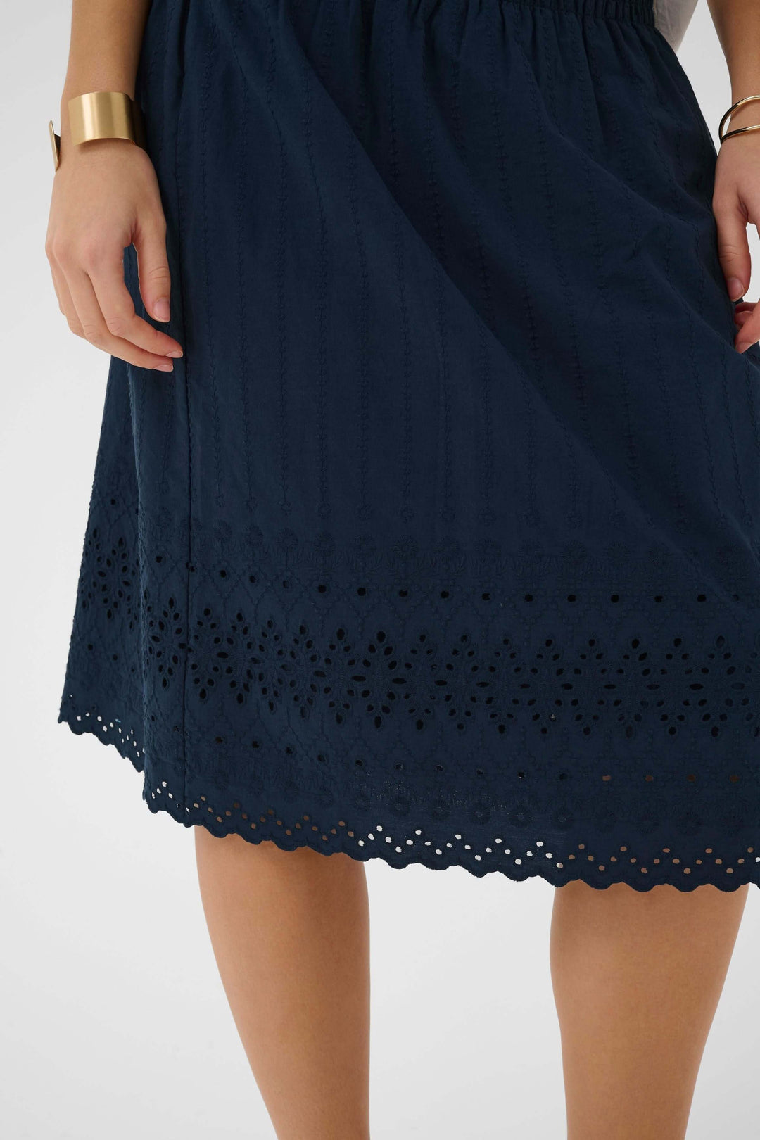 Jupe midi brodée à taille élastique avec broderie ajourée et finition festonnée, idéale pour un look féminin et confortable en été.