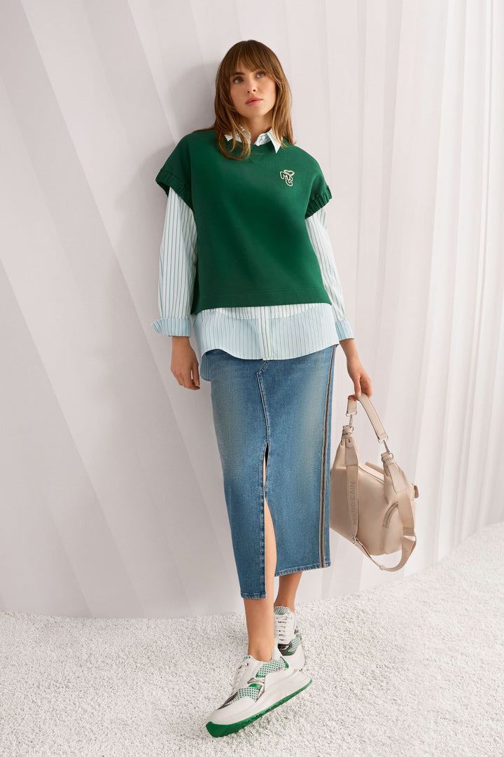 Jupe midi en jean à rayures latérales avec fente centrale, portée avec un haut vert et sac beige.