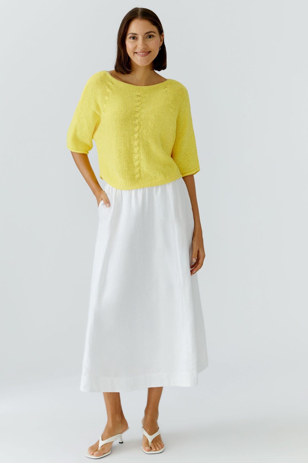 Femme portant une jupe midi fluide blanche avec haut jaune, illustrant une tenue élégante et confortable pour un style quotidien.