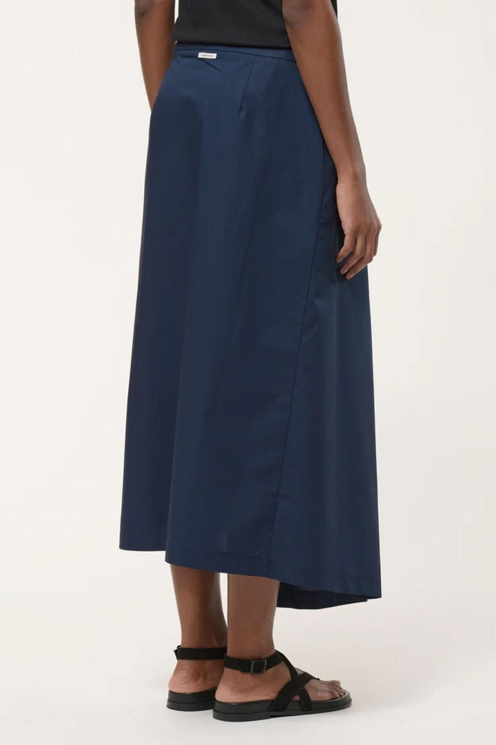 Jupe midi portefeuille élégante en tissu léger bleu, vue arrière sur modèle, offrant une silhouette contemporaine et sophistiquée.