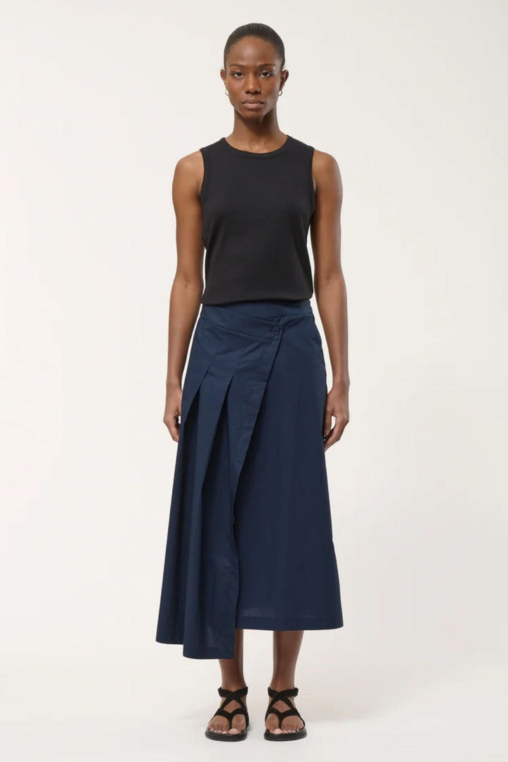 Jupe midi portefeuille bleue avec une coupe portefeuille élégante et contemporaine, portée avec un débardeur noir, créant un look sophistiqué.