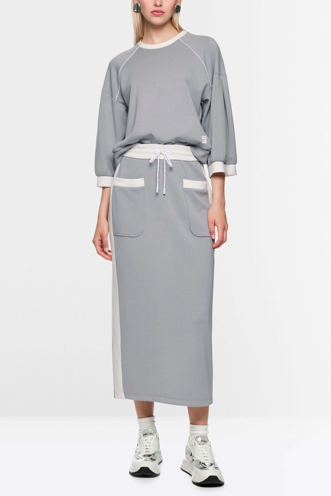 Jupe midi sportive grise avec taille élastiquée, cordon et poches contrastées. Fente arrière pour mobilité. Parfaite pour un style athlétique.