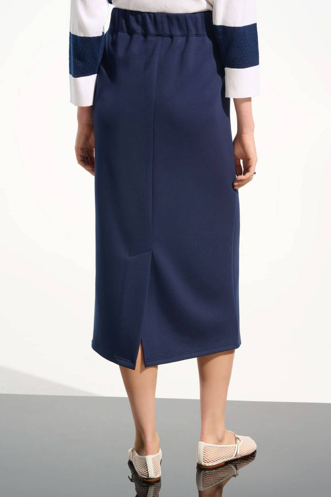 Femme portant une jupe midi à taille coulissante bleue avec cordon de serrage et fente arrière, style décontracté et chic.