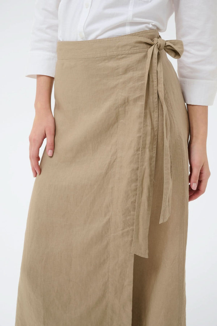 Jupe porte-feuille Arbella en lin beige avec taille ajustable et lien à nouer, offrant une silhouette fluide et élégante.